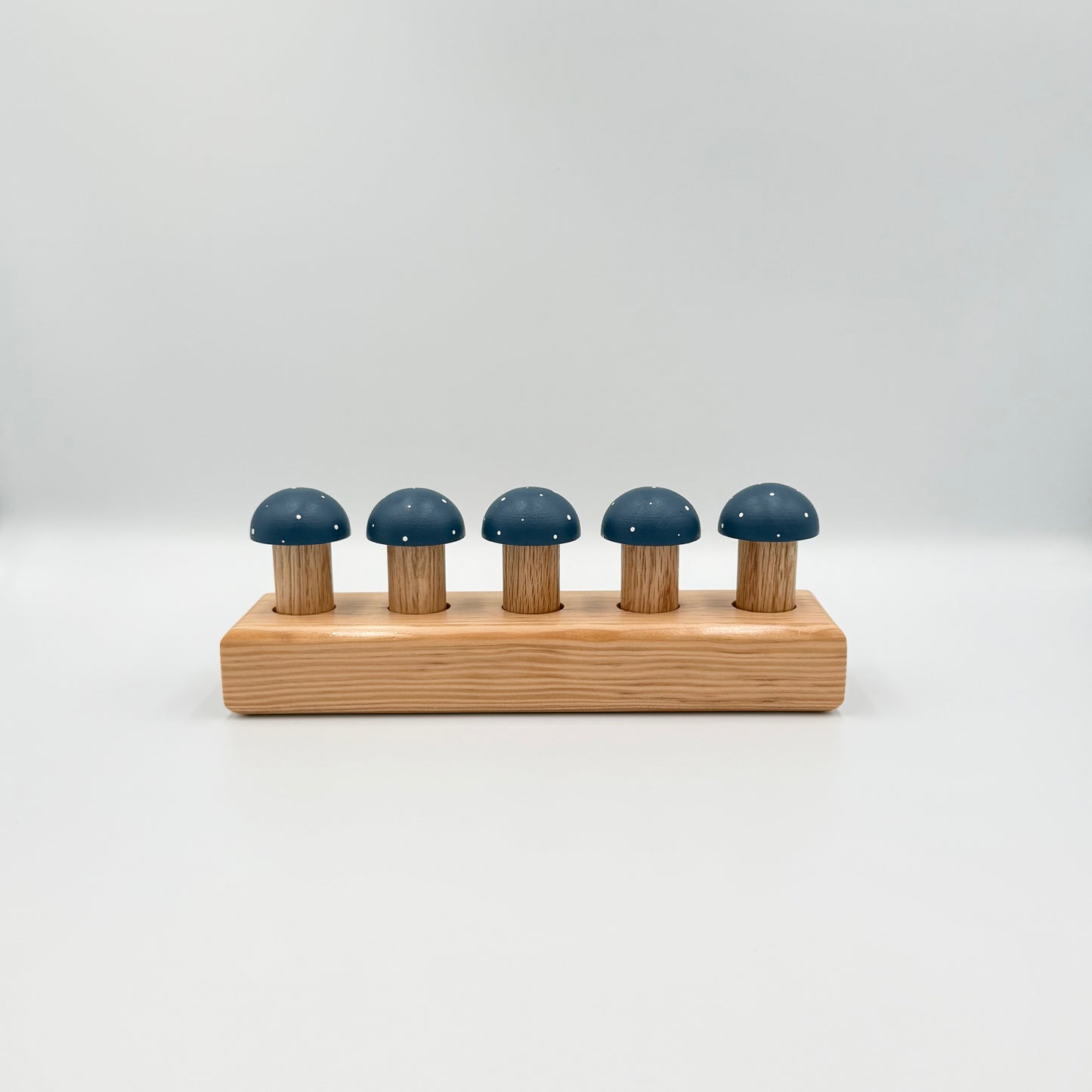 Blue mushroom-shaped playing pegs sitting in a wooden block on a white background