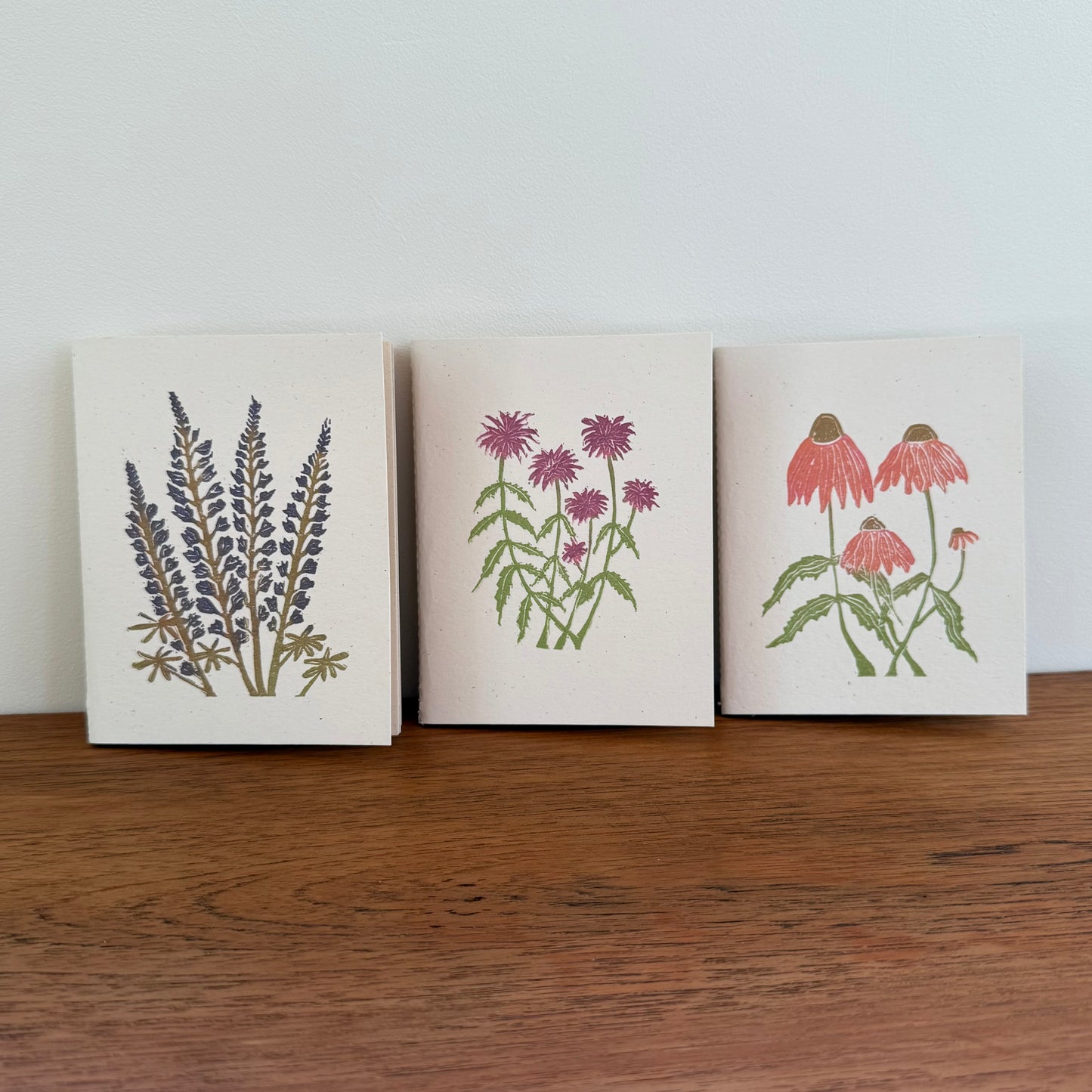 Three notebooks with floral designs on a wooden surface