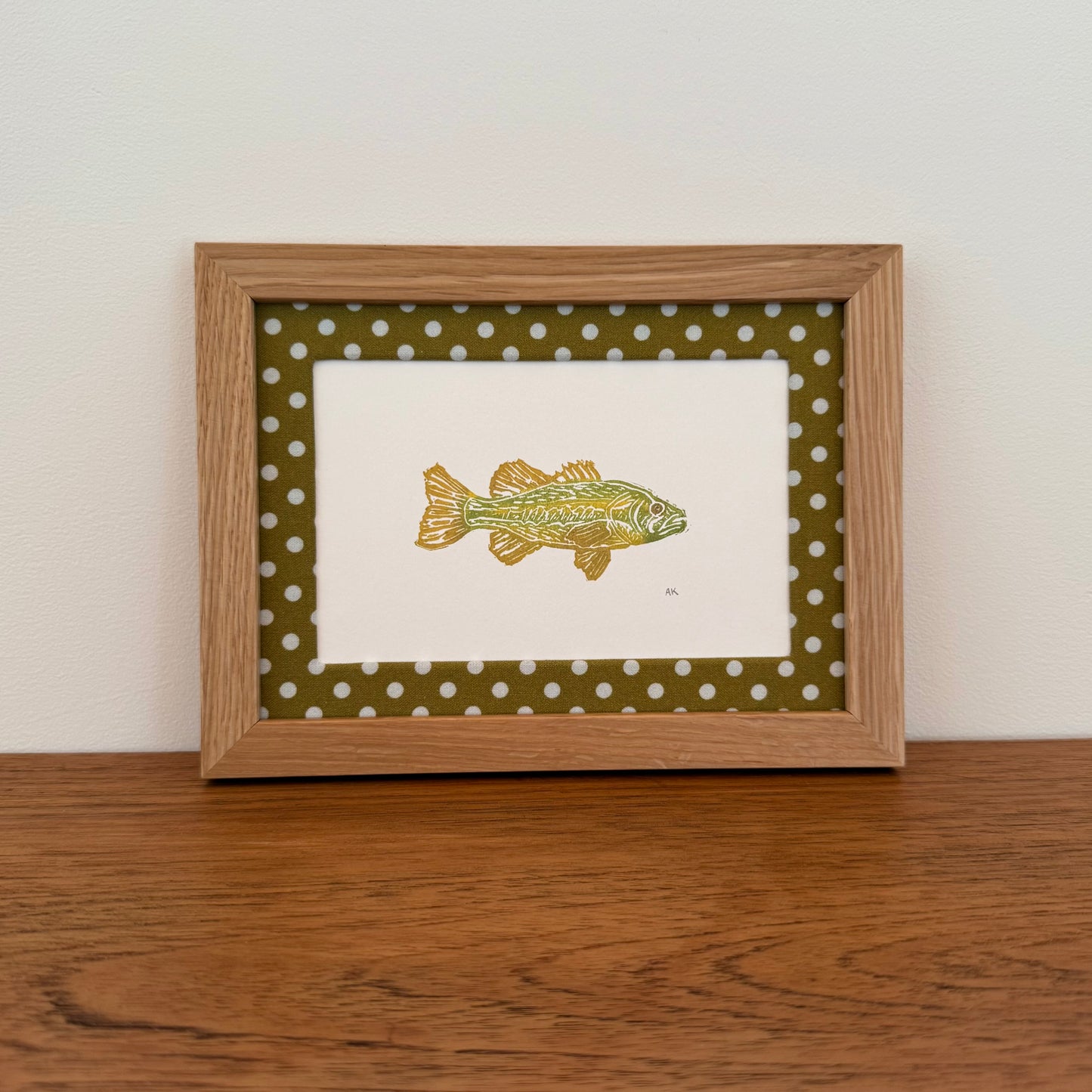 Framed artwork with a bass design on a wooden surface and white wall background