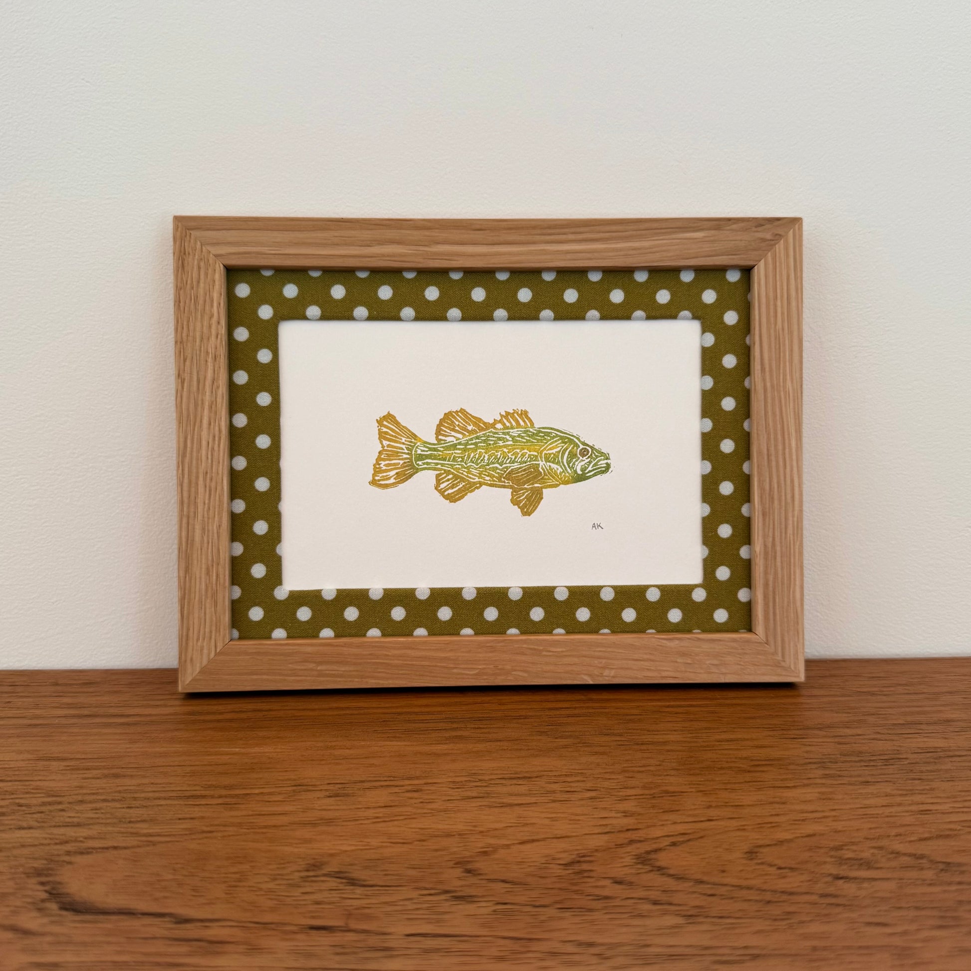 Framed artwork with a bass design on a wooden surface and white wall background