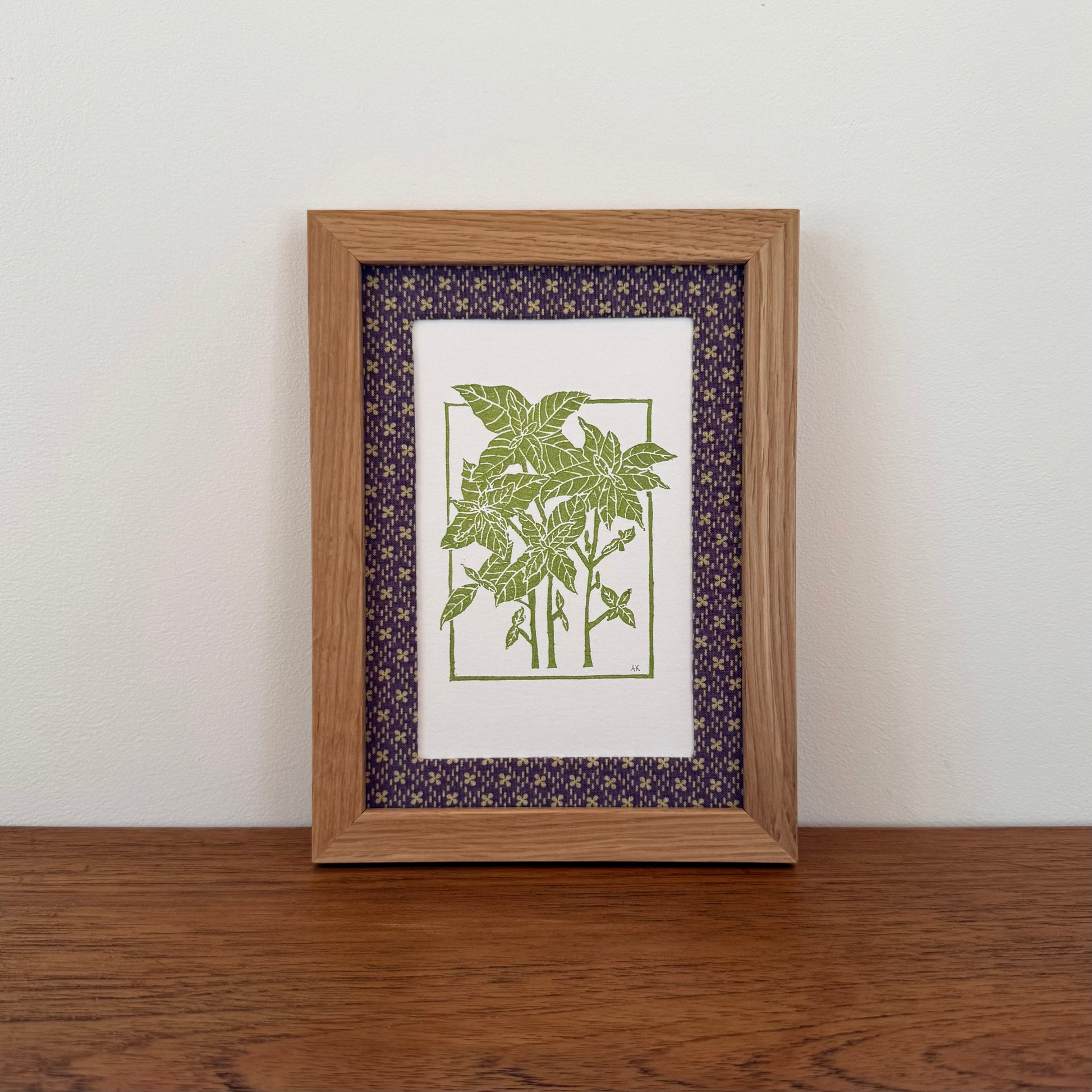 Framed artwork with a basil design on a wooden surface and white wall background