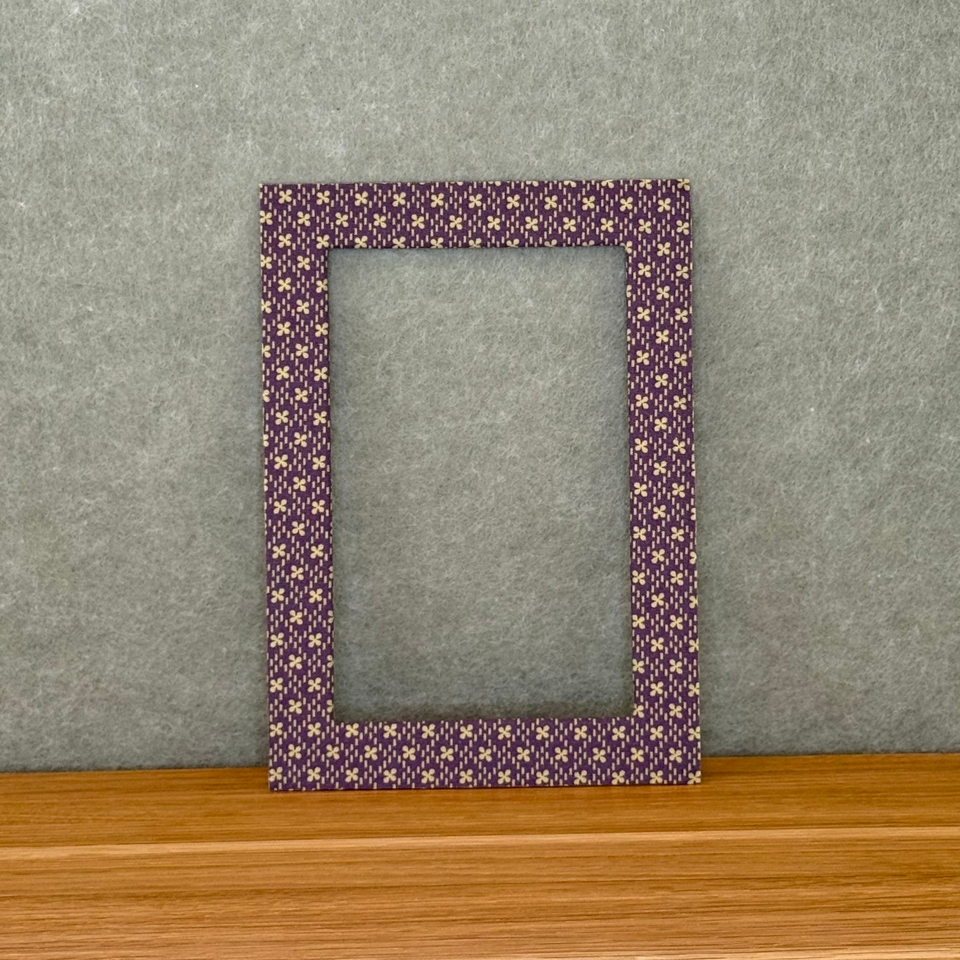 Purple and green patterned photo mat on a wooden surface with a gray background