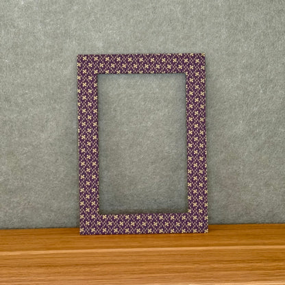 Purple and green patterned photo mat on a wooden surface with a gray background