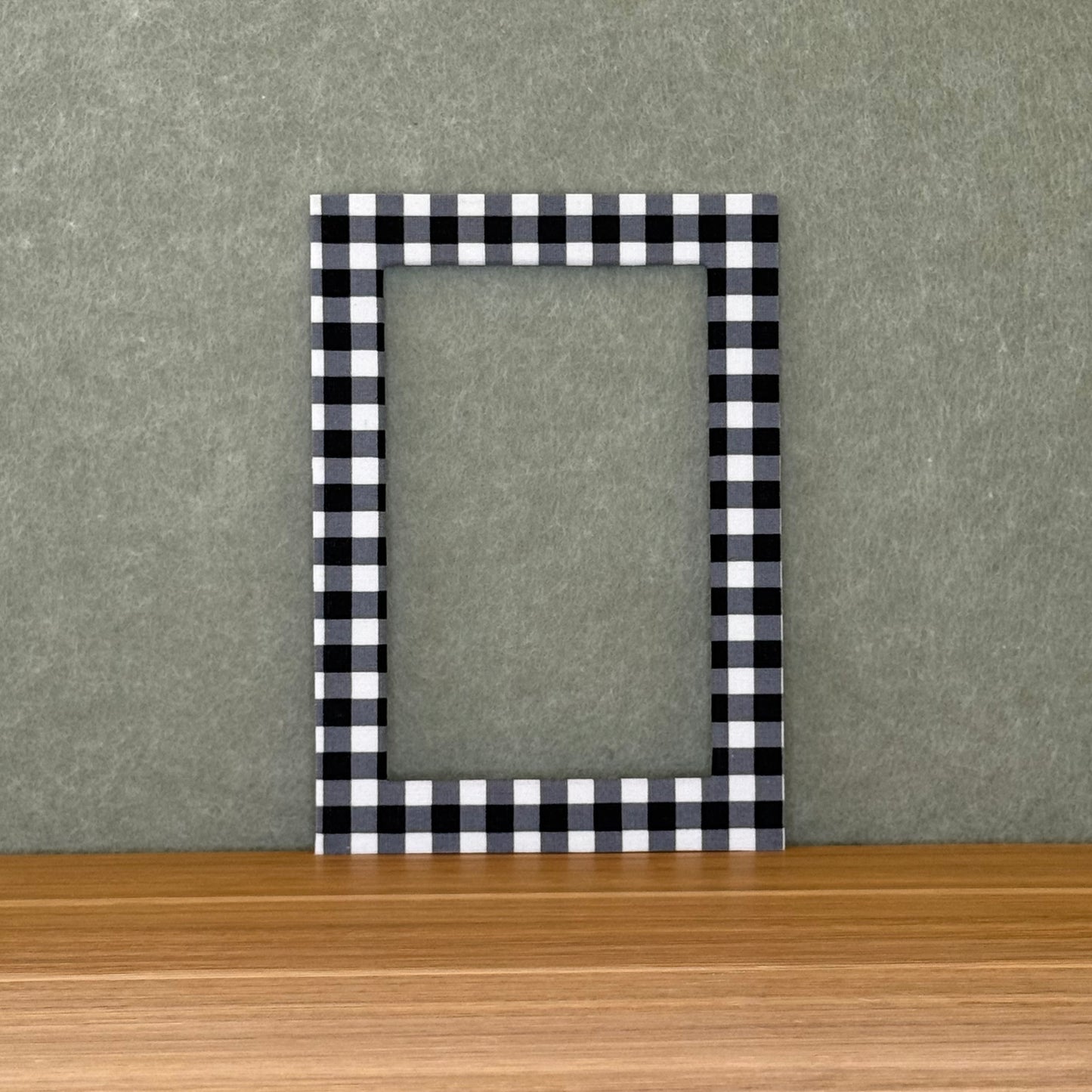 Black and white checkered photo mat on a wooden surface with a gray background