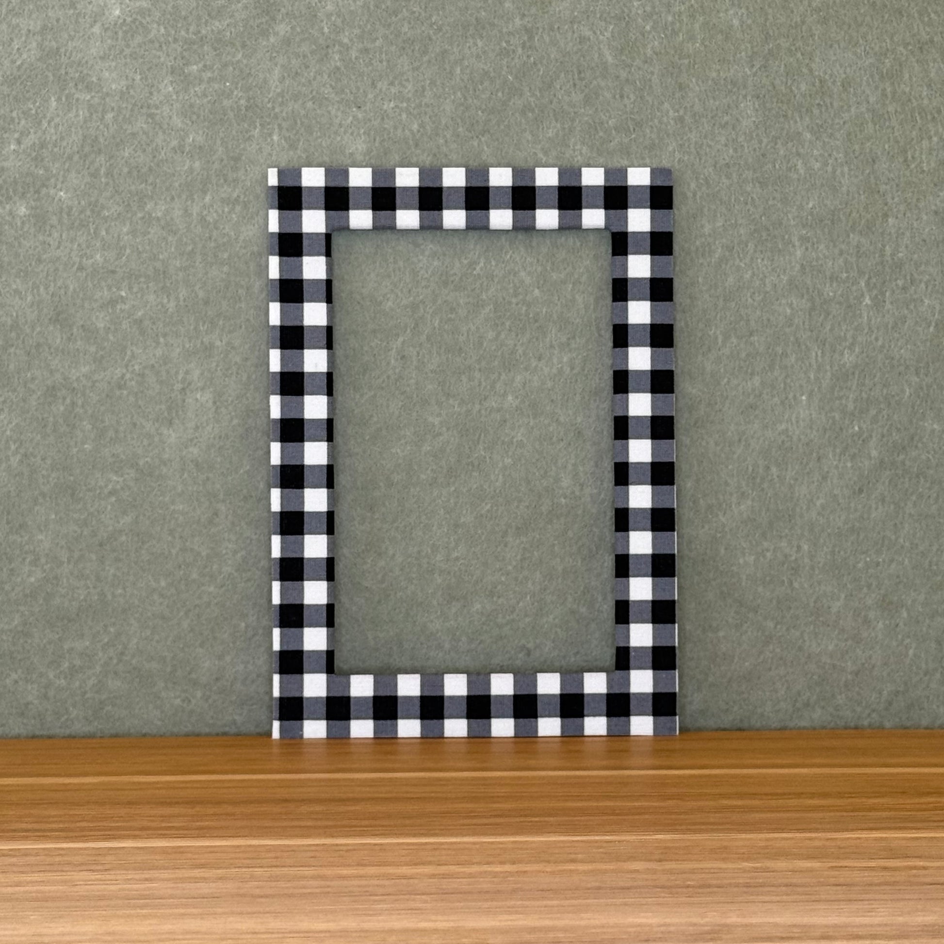 Black and white checkered photo mat on a wooden surface with a gray background