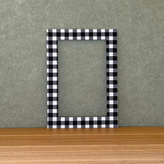 Black and white checkered photo mat on a wooden surface with a gray background