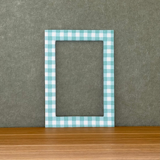 teal and white checkered photo mat on a wooden surface and green wall background