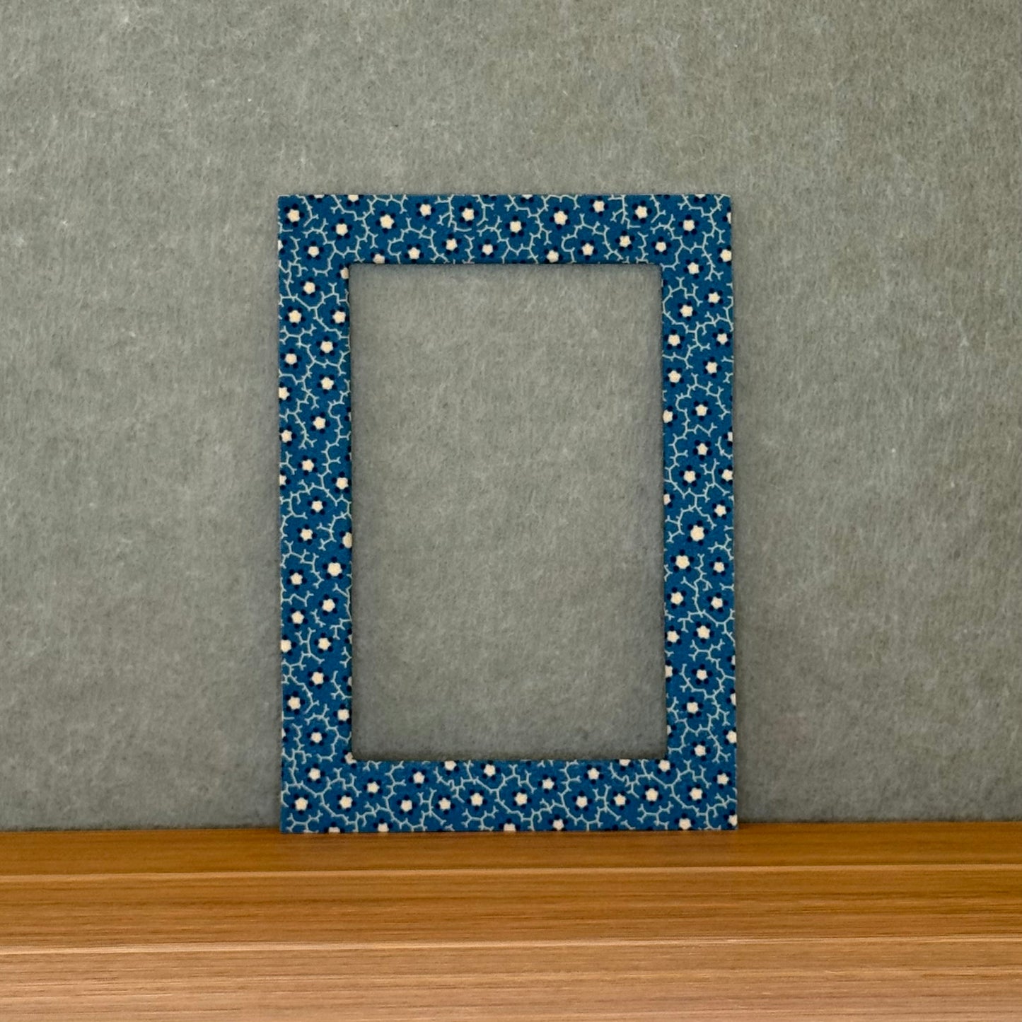 Blue floral patterned mat sitting on a wood surface with  a green background.