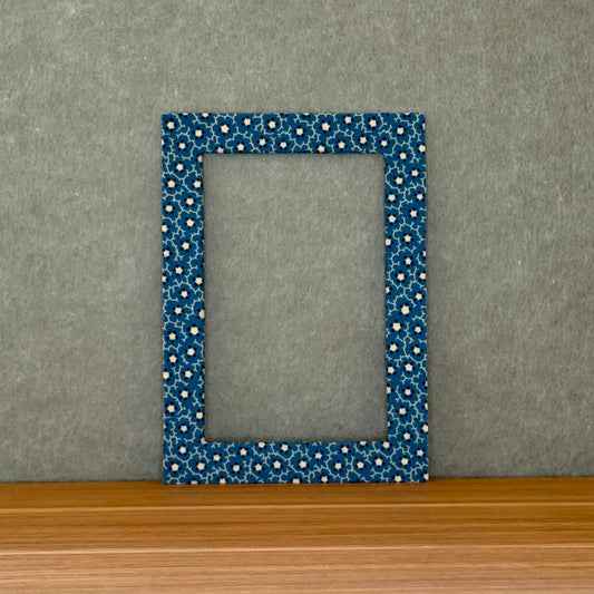Blue floral patterned mat sitting on a wood surface with  a green background.