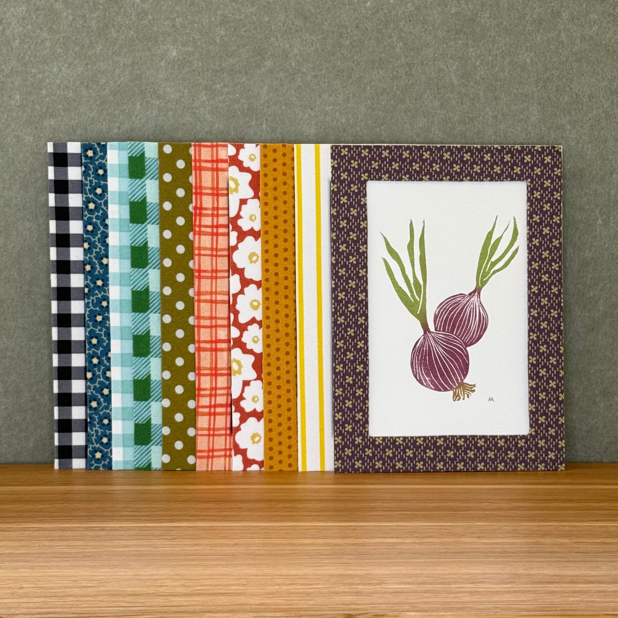 Set of fabric wrapped photo mats with various patterns on a wooden surface and gray background