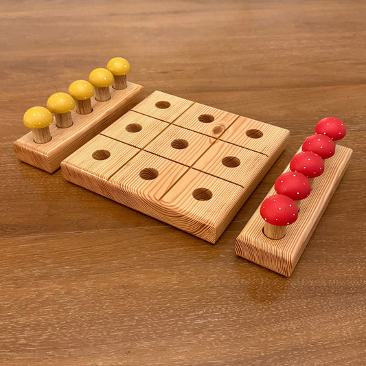 Wooden mushroom tic tac toe game on a wooden surface.  The game includes red and yellow mushroom playing pegs.