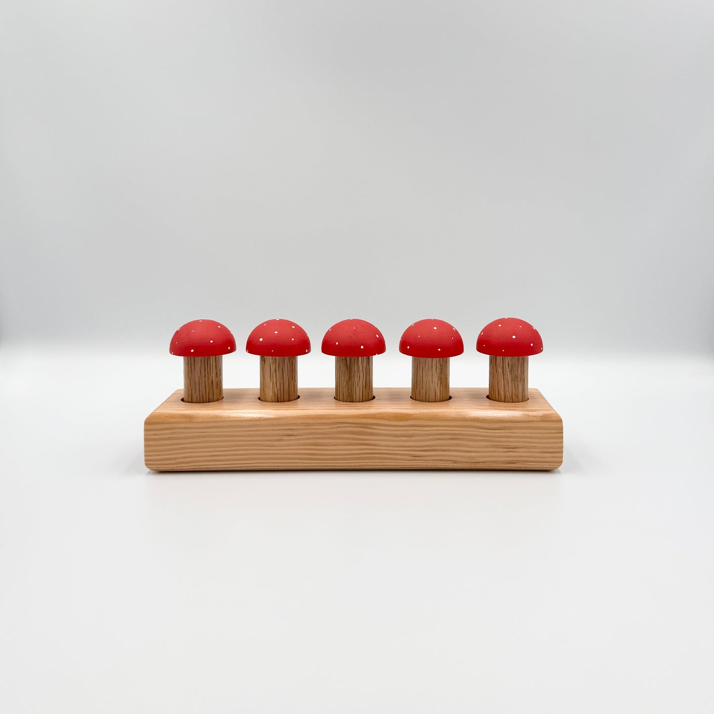 Red mushroom-shaped playing pegs sitting in a wooden block on a white background