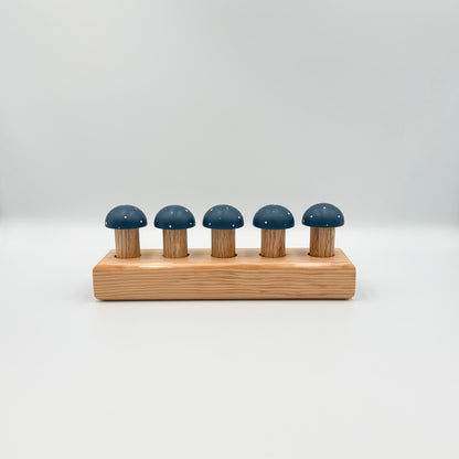 Blue mushroom-shaped playing pegs sitting in a wooden block on a white background