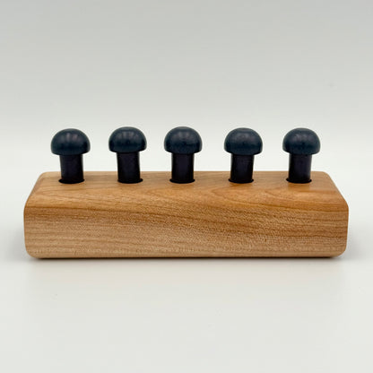 A wooden playing peg holder with dark blue mushroom-shaped playing pieces, shown on a light gray background.