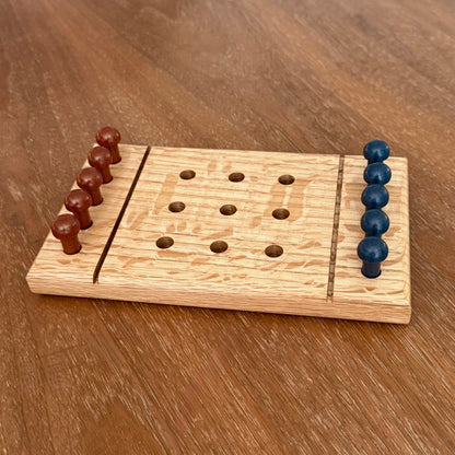 A small wooden tic-tac-toe game board  sitting on a table with rust colored playing pegs and dark blue colored playing pegs.
